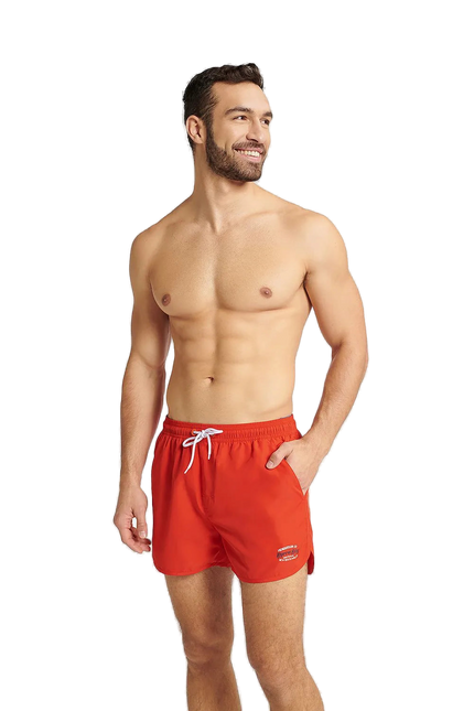 Homme portant un short de bain rouge GUILD à séchage rapide, avec une taille élastique réglable et des détails contrastés. Modèle confortable et tendance, idéal pour la plage et les activités aquatiques. Disponible en tailles M, L, XL, XXL.