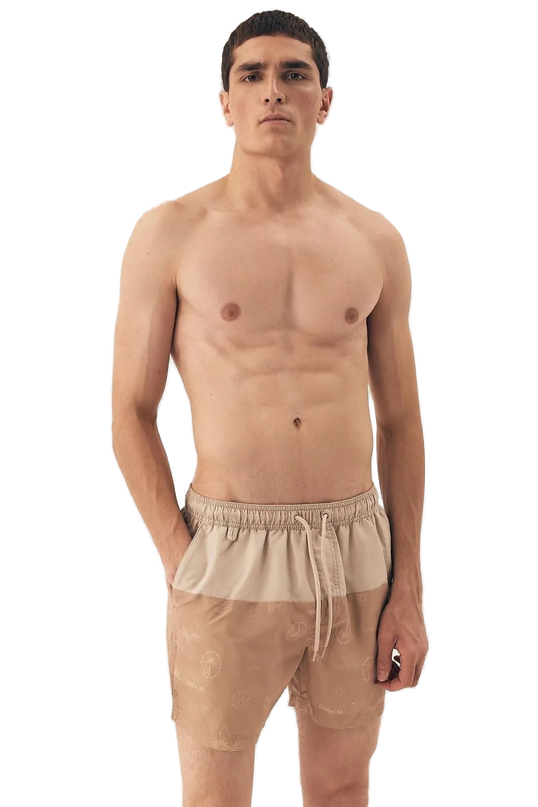 Homme portant un short de bain beige avec des motifs tropicaux subtils, inspiré du style décontracté et festif des plages brésiliennes, idéal pour une promenade en bord de mer ou un moment de détente.