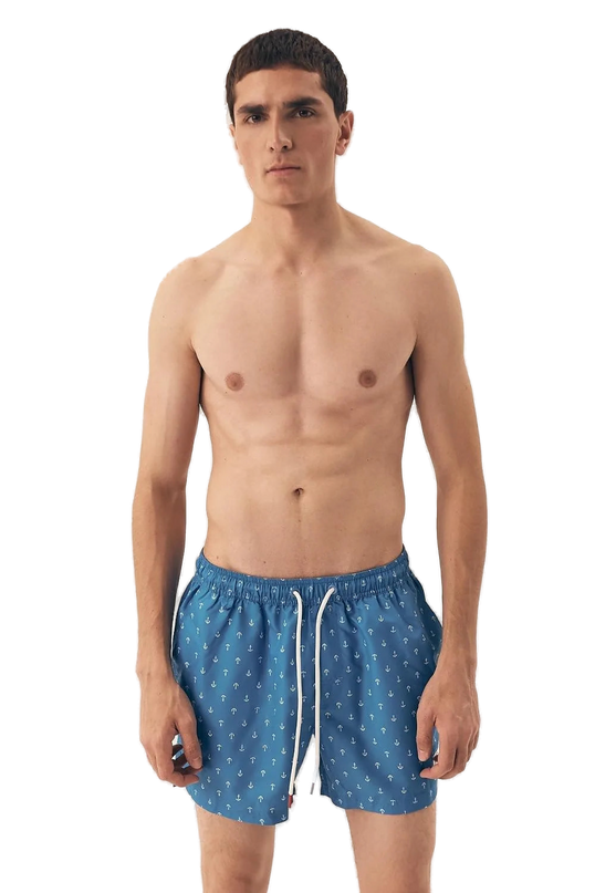 Homme portant un maillot de bain bleu à motifs d'ancres marines, inspiré des plages brésiliennes, alliant style décontracté et élégance tropicale. Parfait pour une journée au bord de l'eau ou une promenade en bord de plage, ce maillot reflète le lifestyle balnéaire moderne et intemporel.