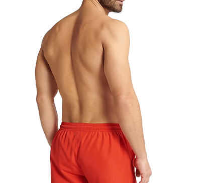 Homme portant un short de bain rouge énergique GUILD à séchage rapide, coupe ample avec taille élastique ajustable, idéal pour la plage et les activités aquatiques.