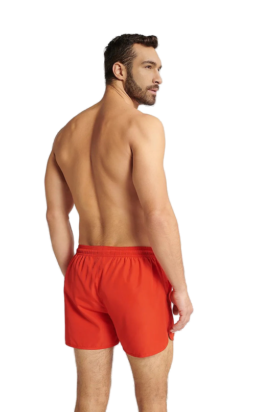 Homme portant un short de bain rouge énergique GUILD à séchage rapide, coupe ample avec taille élastique ajustable, idéal pour la plage et les activités aquatiques.
